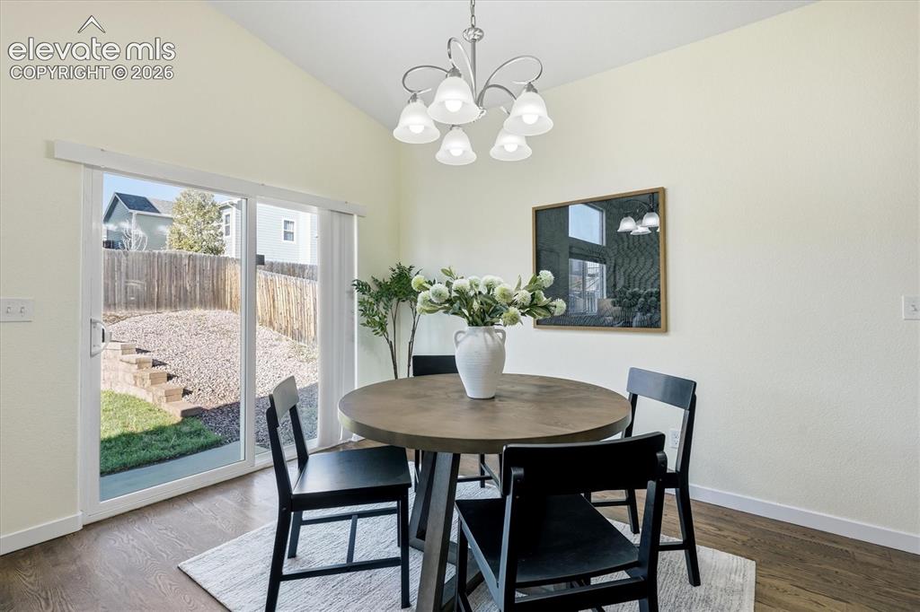 Image 15 of 45: Vaulted ceiling with a central chandelier, wood-finish flooring, and slidin