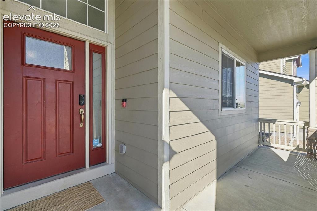 Image 3 of 45: Inviting covered front porch with a paneled entry door, sidelight, and tran