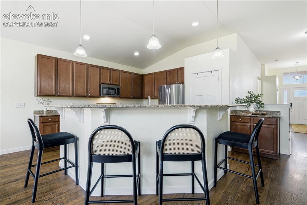 Image 8 of 45: Kitchen featuring a breakfast bar with granite countertops, wood-finish flo