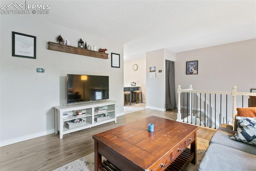Image 10 of 28: Living area with wood finished floors and a textured ceiling