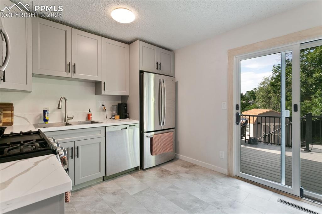 Image 11 of 28: Kitchen featuring stainless steel appliances, gray cabinets, a textured cei