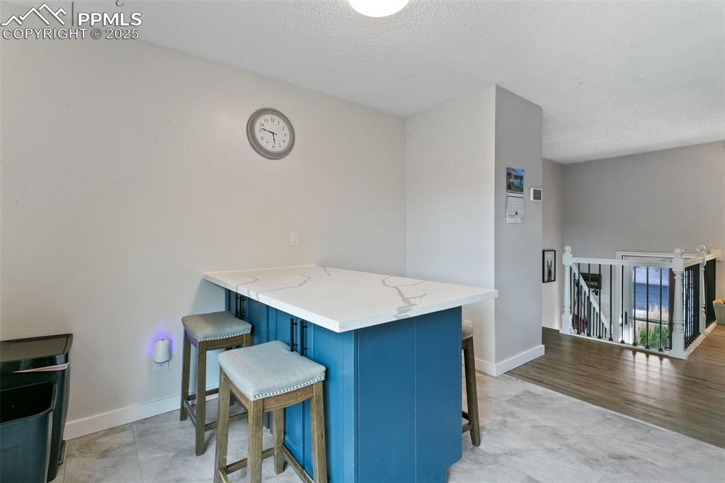 Image 15 of 28: Kitchen featuring blue cabinets, a kitchen breakfast bar, a peninsula, ligh