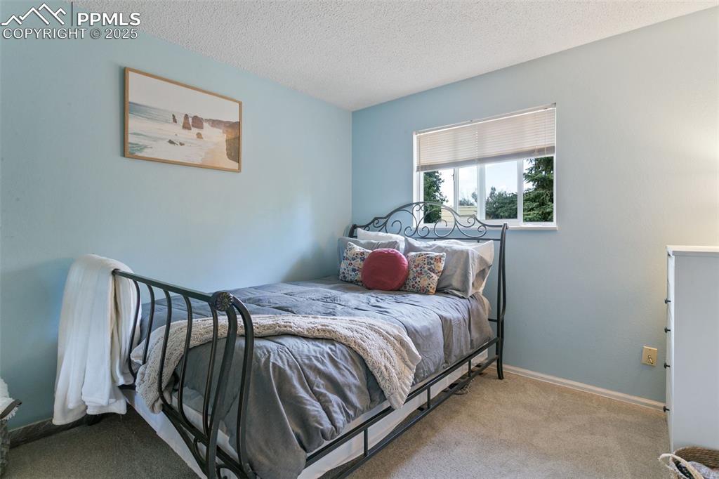 Image 24 of 28: Carpeted bedroom featuring a textured ceiling and baseboards