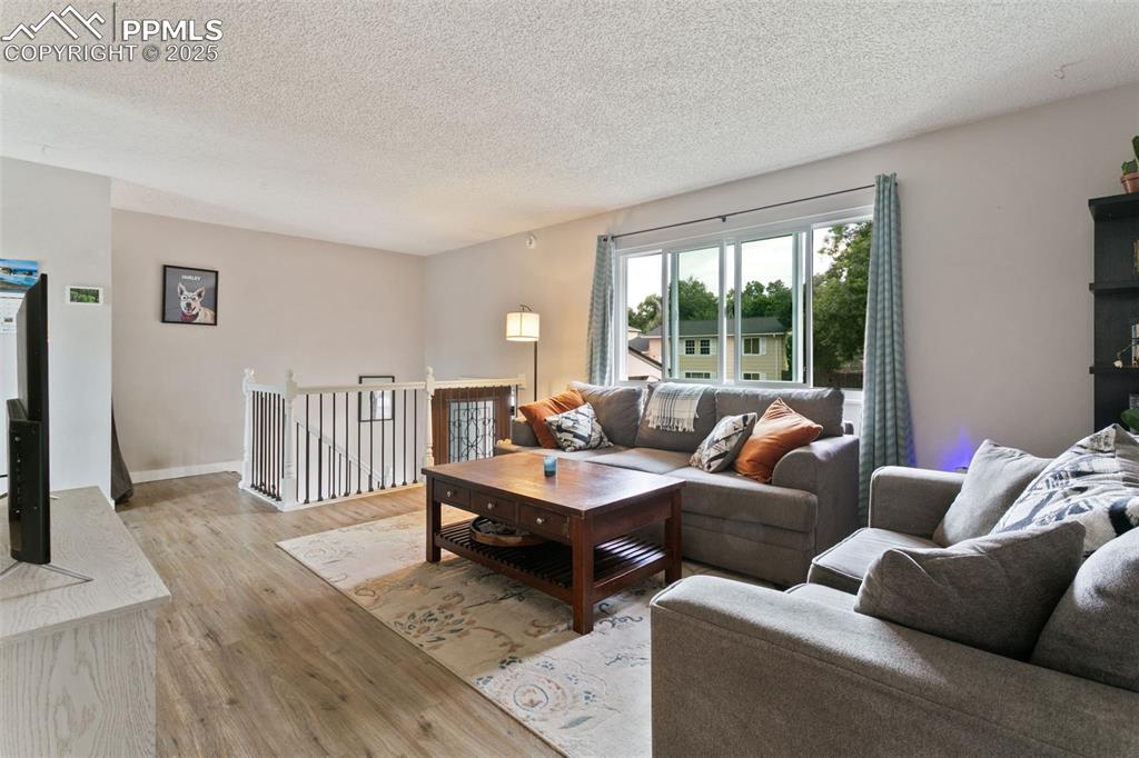 Image 7 of 28: Living area featuring a textured ceiling and wood finished floors
