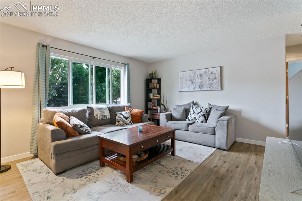 Image 8 of 28: Living area with a textured ceiling and light wood finished floors