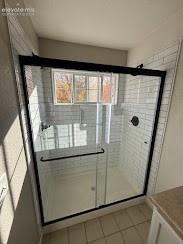 Image 6 of 41: Glass-enclosed shower with subway tile surround, matte black fixtures, and
