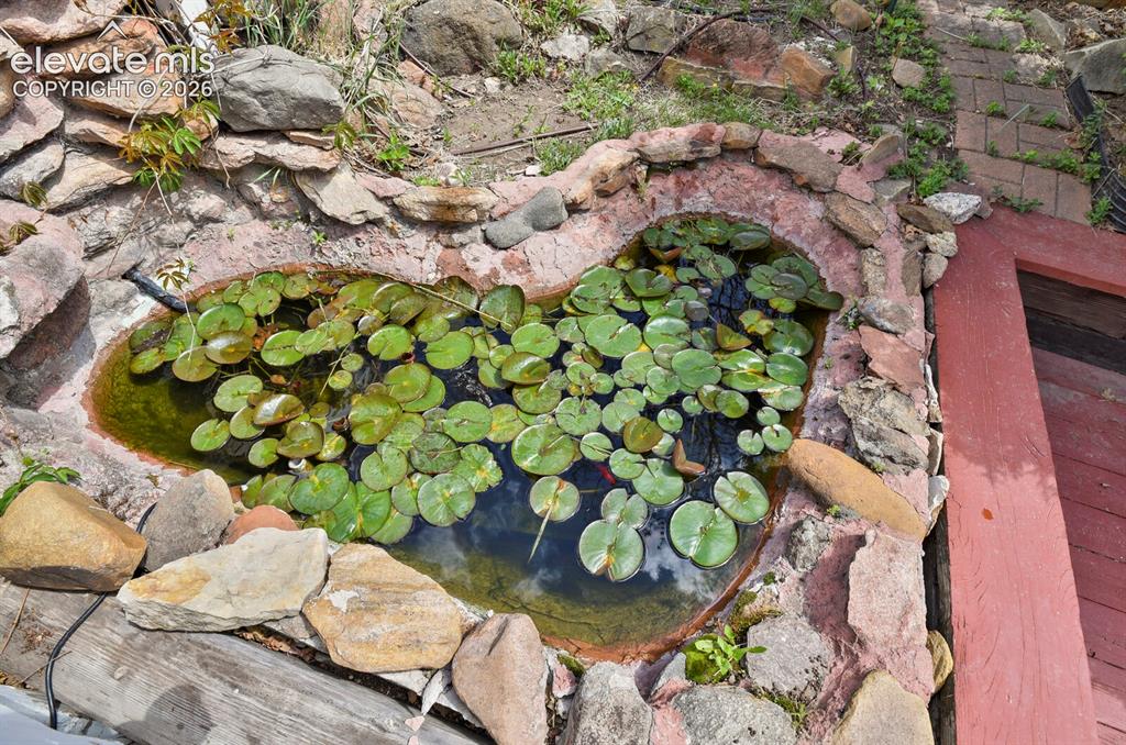 Image 29 of 37: Waterfall cascades into the lily pad pond with goldfish 