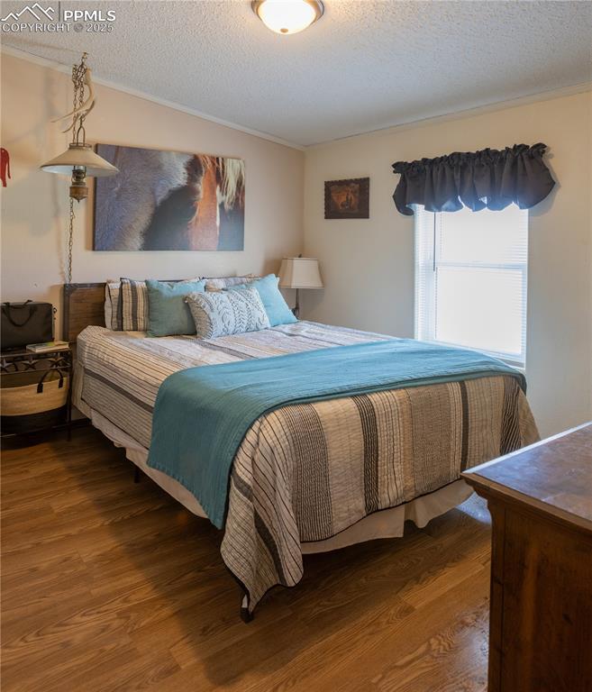 Image 19 of 50: Bedroom with crown molding, wood finished floors, and a textured ceiling