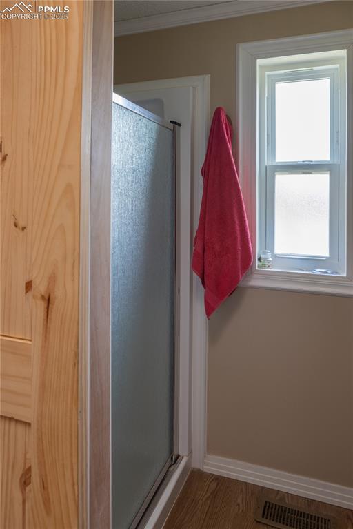Image 21 of 50: Full bathroom with a stall shower, ornamental molding, and wood finished fl