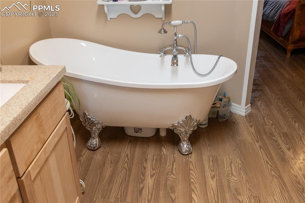 Image 23 of 50: Full bath with vanity, wood finished floors, and a freestanding tub