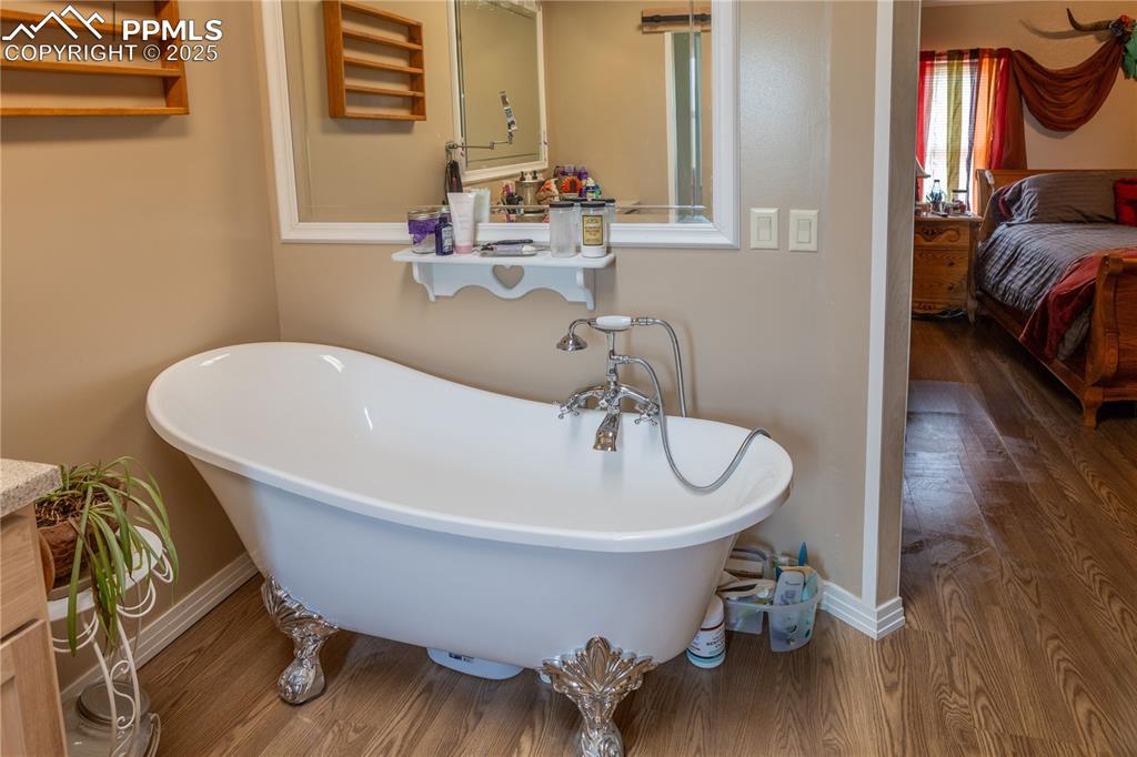 Image 24 of 50: Ensuite bathroom with wood finished floors and a freestanding bath