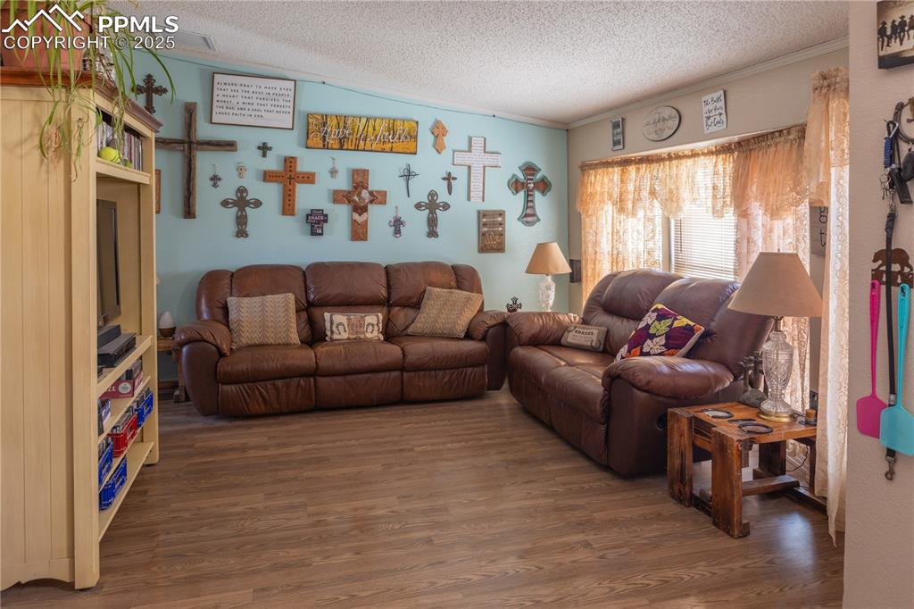 Image 28 of 50: Living area featuring wood finished floors, a textured ceiling, and crown m