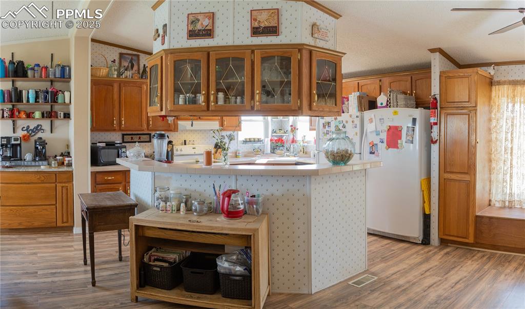 Image 47 of 50: Kitchen with vaulted ceiling, light wood finished floors, a ceiling fan, br