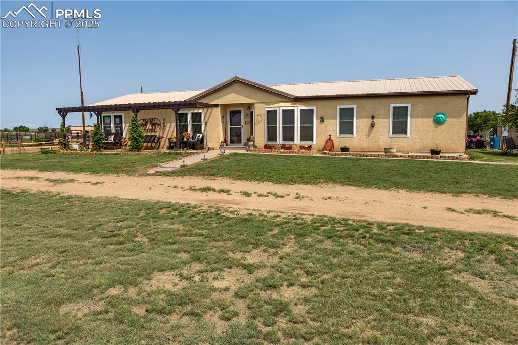 Image 48 of 50: Ranch-style house featuring a front lawn, a pergola, stucco siding, and a m