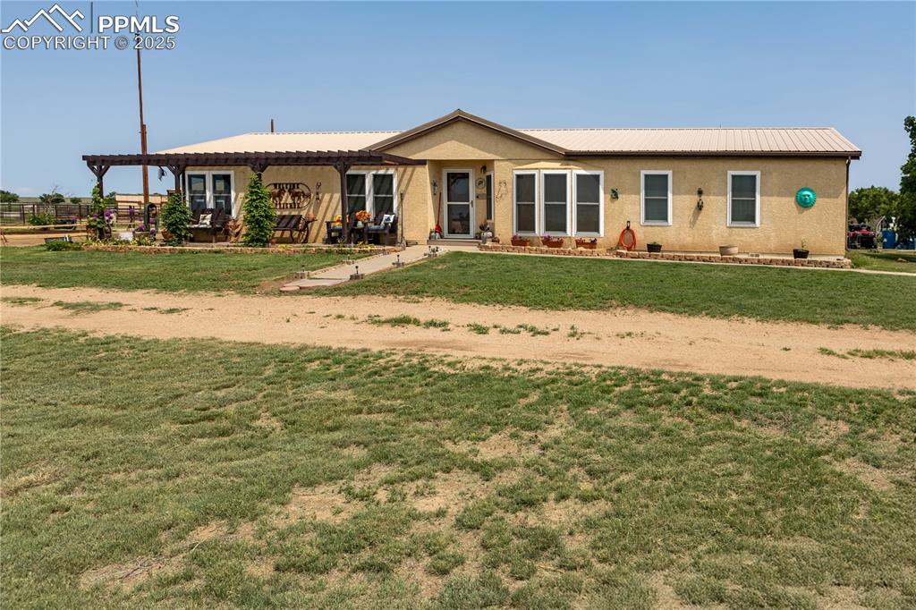 Image 49 of 50: Ranch-style house with a pergola, a front lawn, stucco siding, and a metal