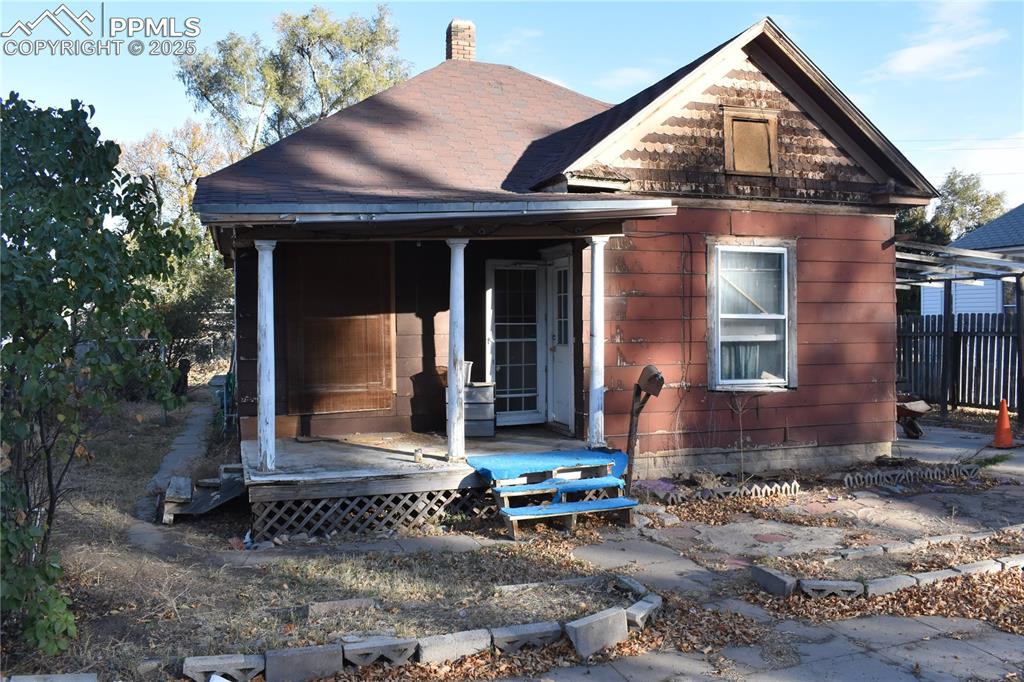 Caption: View of front of house featuring a chimney and covered porch
