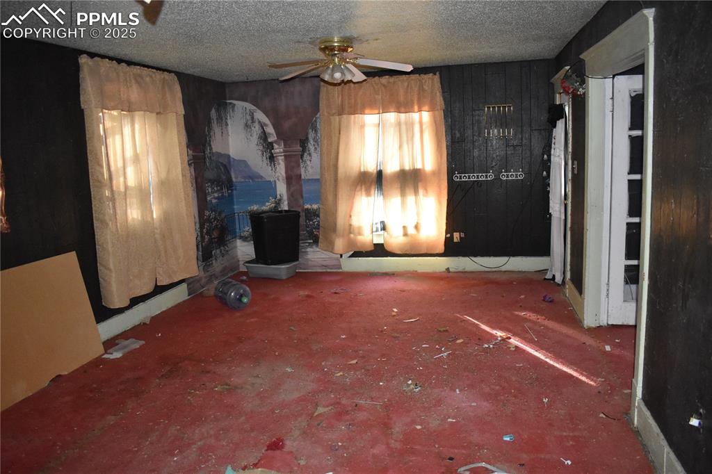 Image 12 of 23: Unfurnished living room with ceiling fan and a textured ceiling