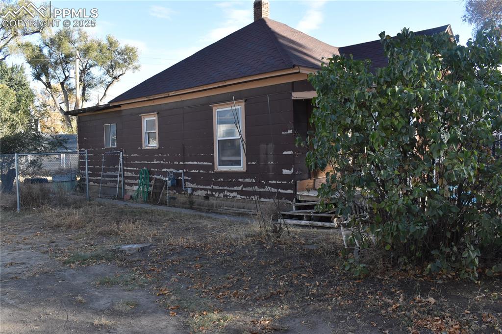 Image 2 of 23: View of side of home with a chimney and roof with shingles