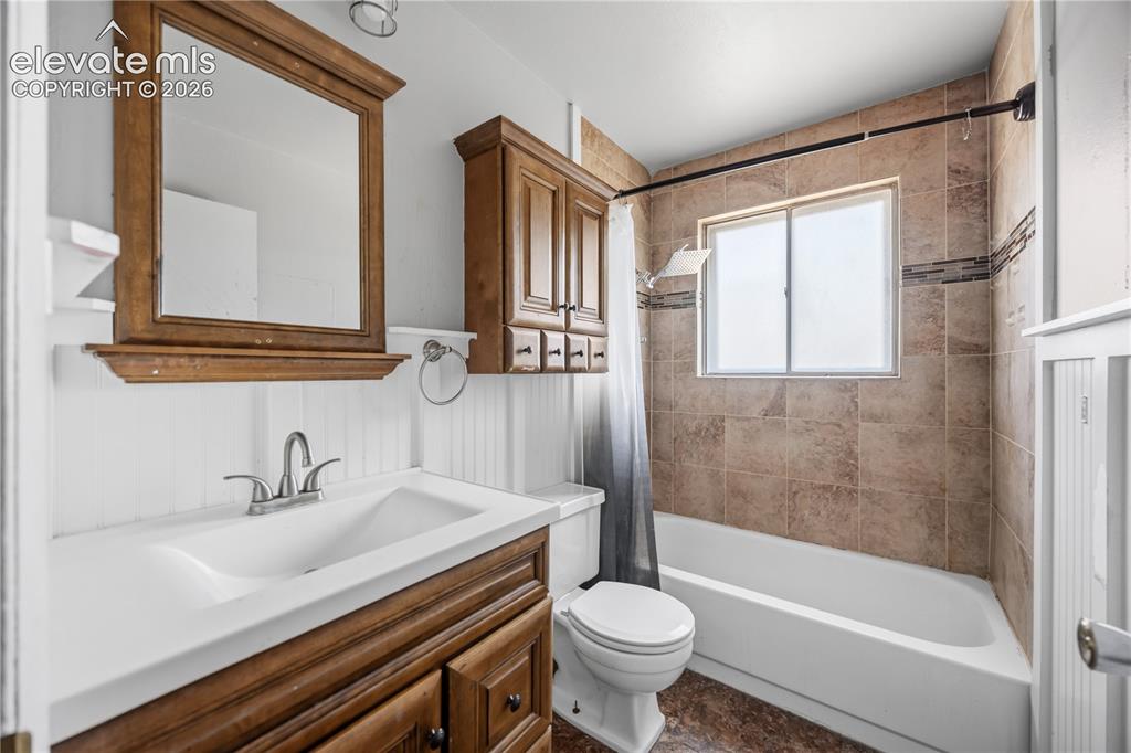 Image 15 of 31: Upper Level Bathroom with vanity, framed mirror, cabinet and tiled tub/show