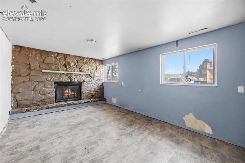 Image 16 of 31: Lower level Family Room with wood burning fireplace, stone surround, and ra