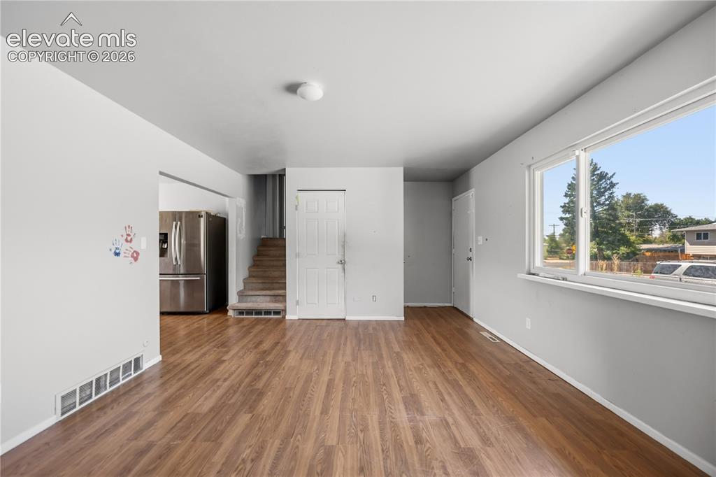 Image 4 of 31: The Living Room opens into the Dining Area and Kitchen with stairs to the u