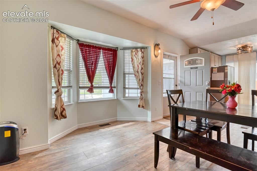 Image 12 of 40: Bay window with wood-finish flooring, featuring a ceiling fan and a paneled
