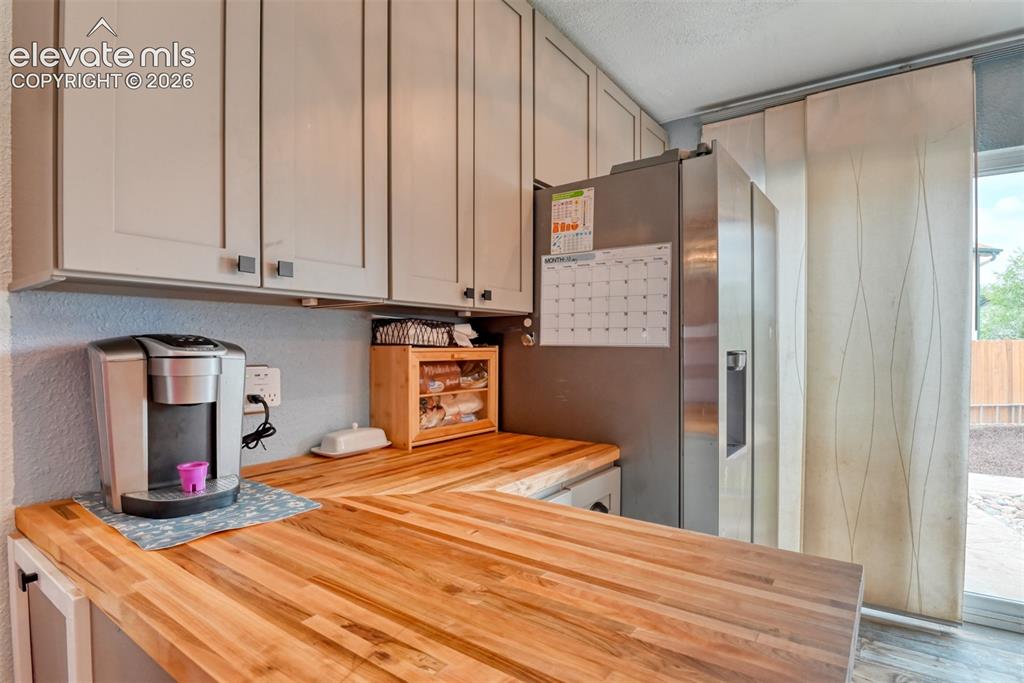 Image 15 of 40: Kitchen featuring light gray cabinetry with dark square hardware, wood-fini