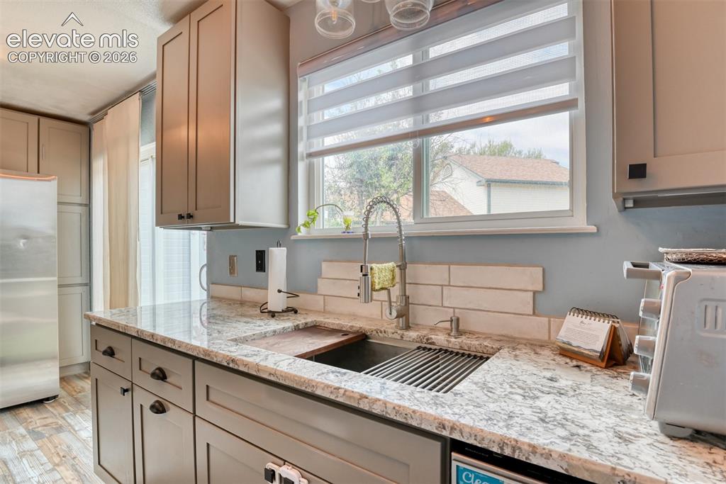 Image 16 of 40: Kitchen featuring light gray cabinetry, speckled countertops, a subway tile