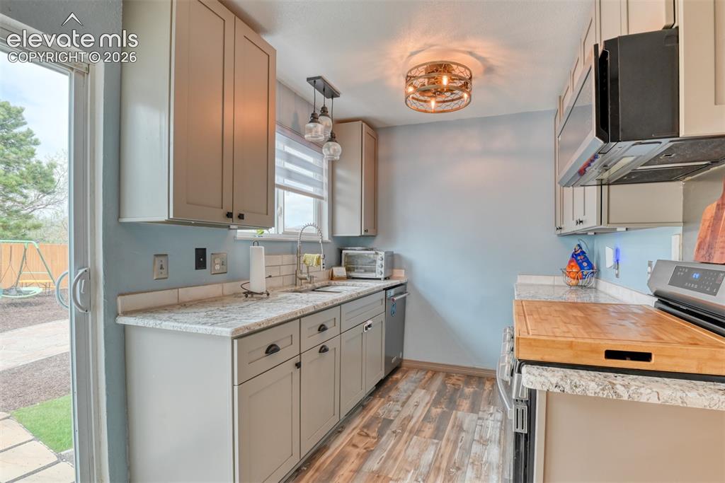 Image 17 of 40: Kitchen featuring light gray cabinetry with dark hardware, a stainless stee