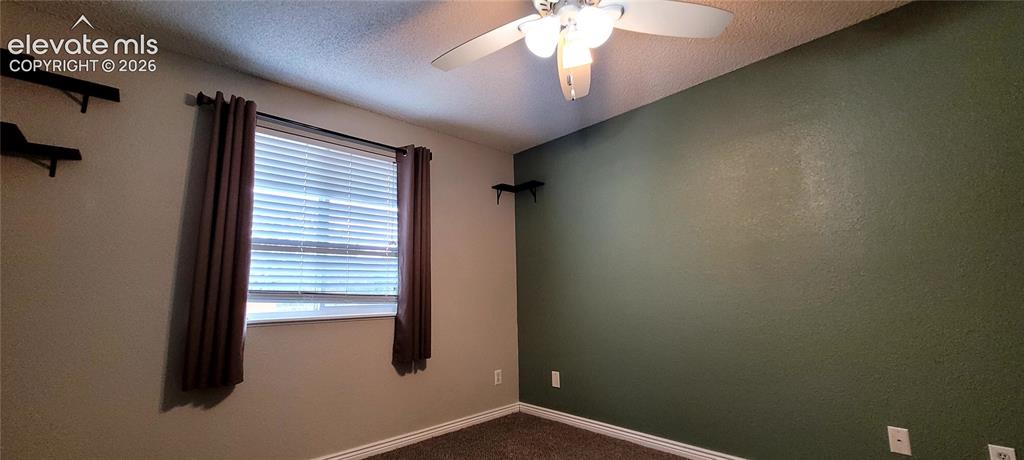 Image 18 of 40: Carpeted room featuring a window with horizontal blinds and drapery panels,
