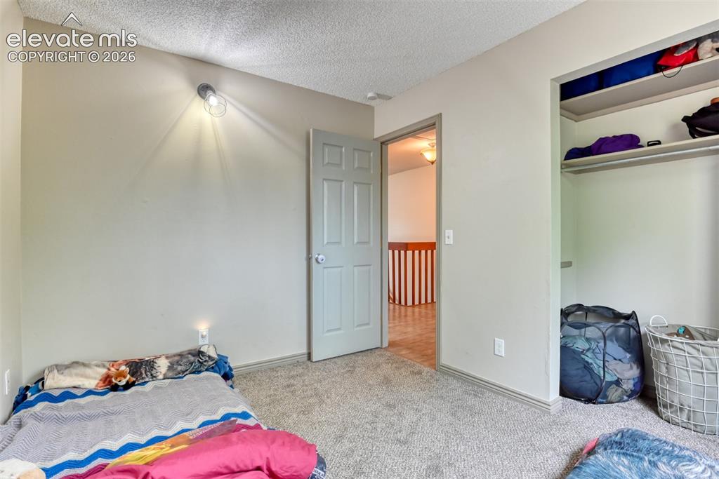 Image 20 of 40: Bedroom featuring light gray wall paint, textured ceiling, a built-in close