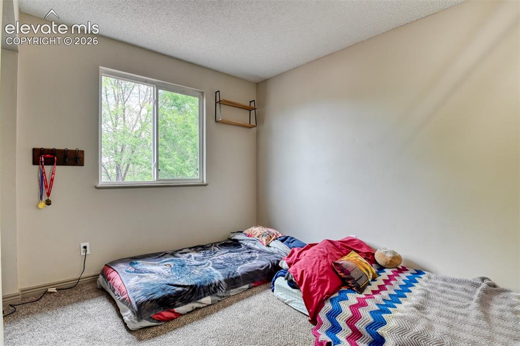 Image 24 of 40: Carpeted interior room featuring a sliding window, light-toned walls, and a