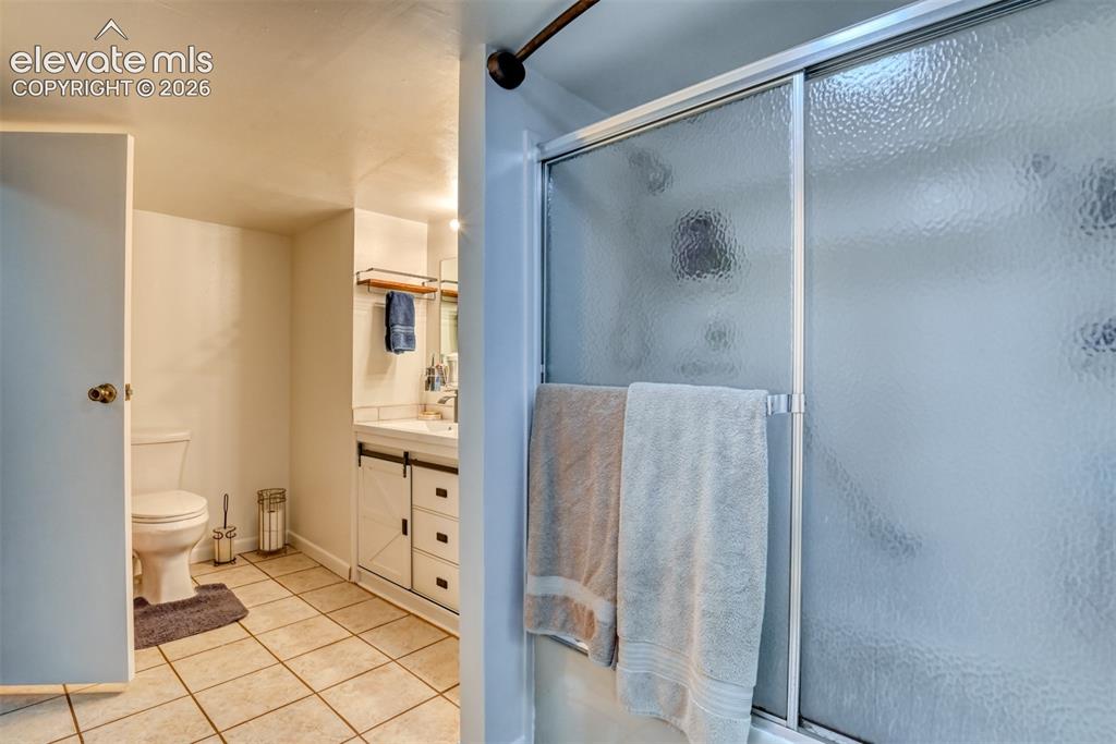 Image 33 of 40: Shower with textured glass sliding doors, alongside a vanity featuring a wh