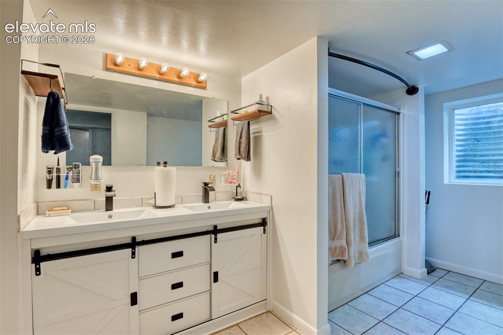 Image 34 of 40: Dual vanity with barn door style cabinetry, integrated sinks, and matte bla
