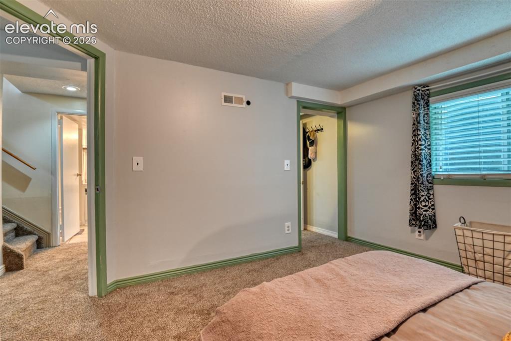 Image 38 of 40: Carpeted room with light grey walls and green trim, featuring a window with