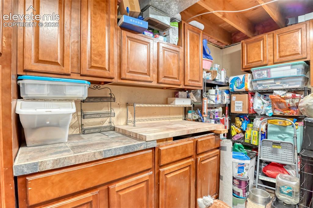 Image 39 of 40: Wood-finish cabinetry with recessed panel doors, tile-finish countertops, a