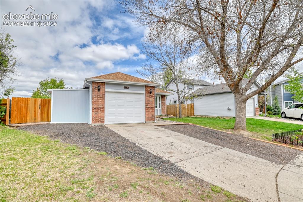 Image 4 of 40: Brick-front home with an attached single-car garage, light blue siding, and