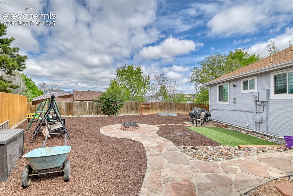 Image 7 of 40: Expansive backyard featuring a natural stone pathway, integrated fire pit, 