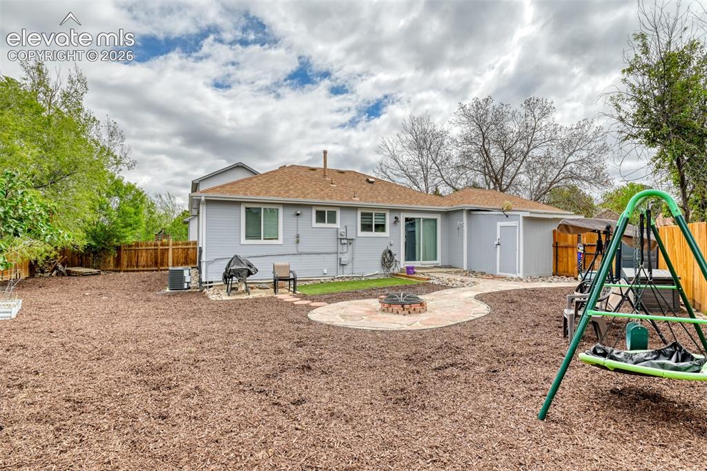 Image 8 of 40: Spacious backyard featuring a large wood chip ground cover and privacy fenc