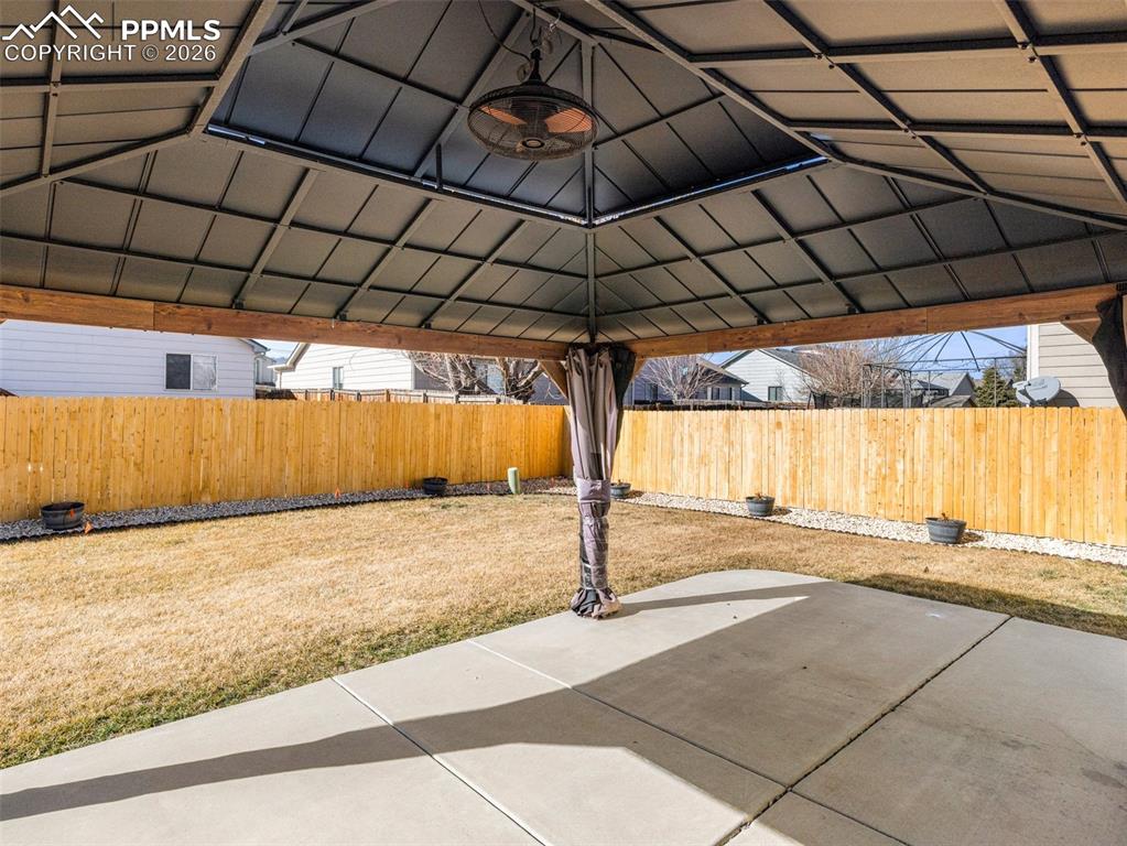 Image 21 of 23: Fenced backyard featuring a a covered patio area
