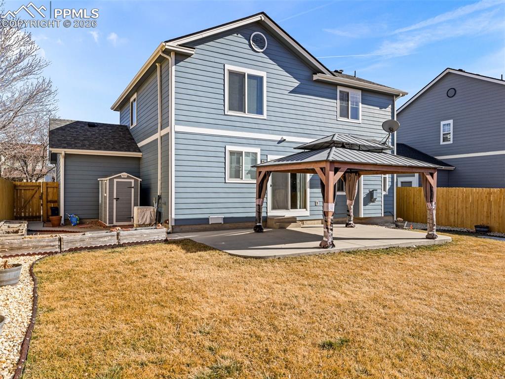 Image 23 of 23: Rear view of property featuring a gazebo, a fenced backyard, storage shed r
