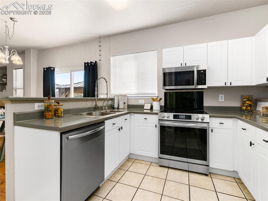 Image 7 of 23: Kitchen with a peninsula, dark countertops, stainless steel appliances, and