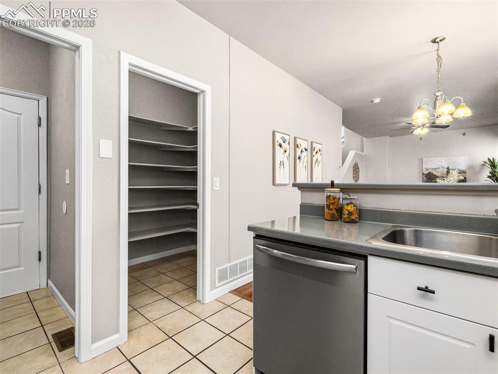 Image 8 of 23: Kitchen with dark countertops, stainless steel dishwasher, white cabinetry,