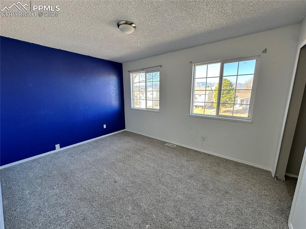Image 11 of 16: Carpeted empty room with a textured ceiling and baseboards