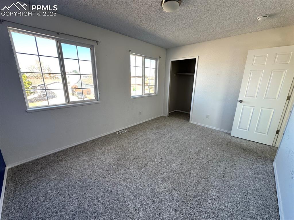 Image 12 of 16: Unfurnished bedroom with carpet flooring, a textured ceiling, and a closet
