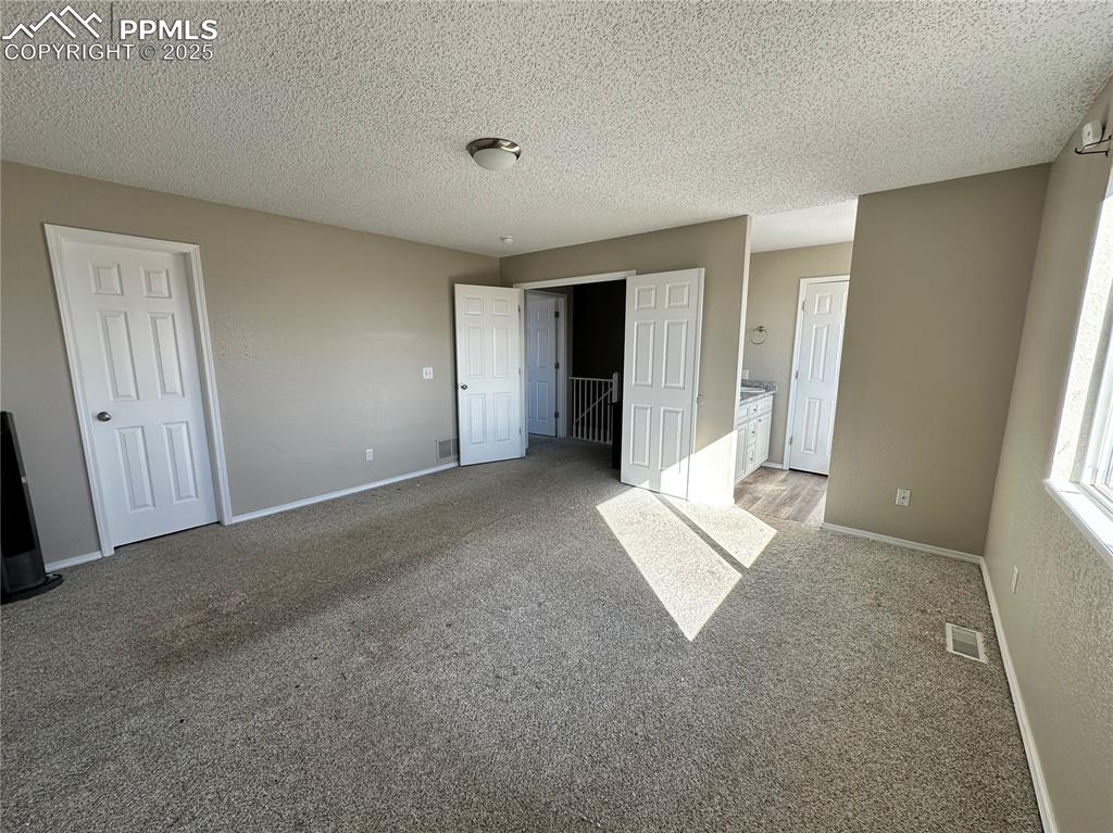 Image 15 of 16: Unfurnished bedroom with carpet floors, ensuite bath, and a textured ceilin