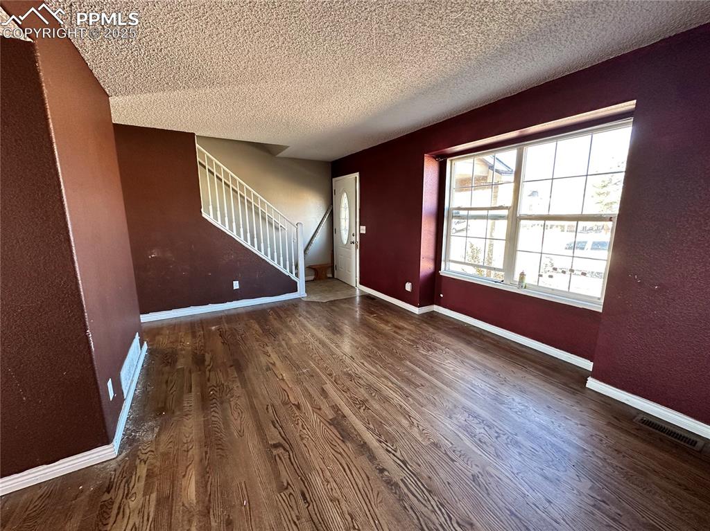 Image 4 of 16: Entryway with dark wood-type flooring, stairs, and a textured ceiling
