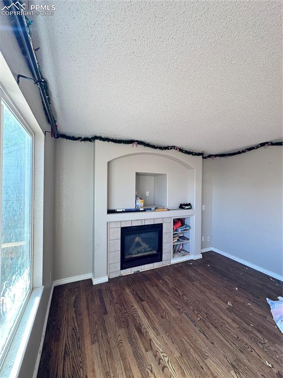 Image 5 of 16: Unfurnished living room with a fireplace, dark wood-style flooring, and a t