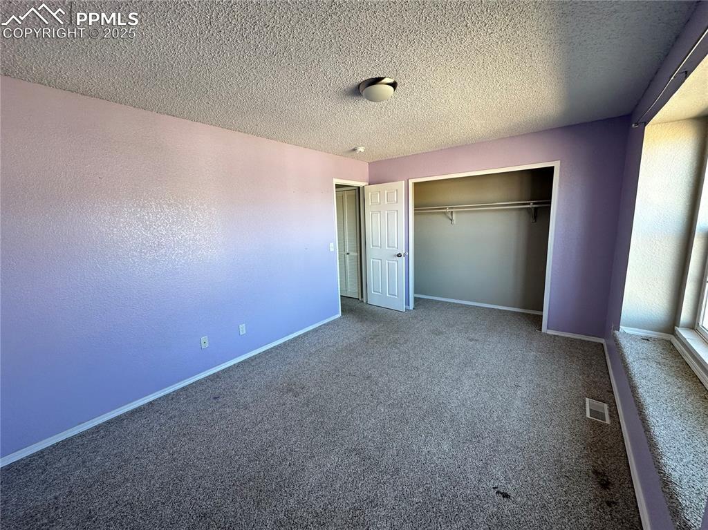 Image 6 of 16: Unfurnished bedroom with carpet flooring, a closet, and a textured ceiling