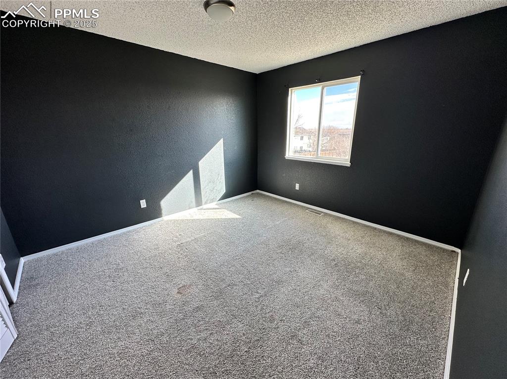 Image 8 of 16: Carpeted empty room featuring a textured wall and a textured ceiling